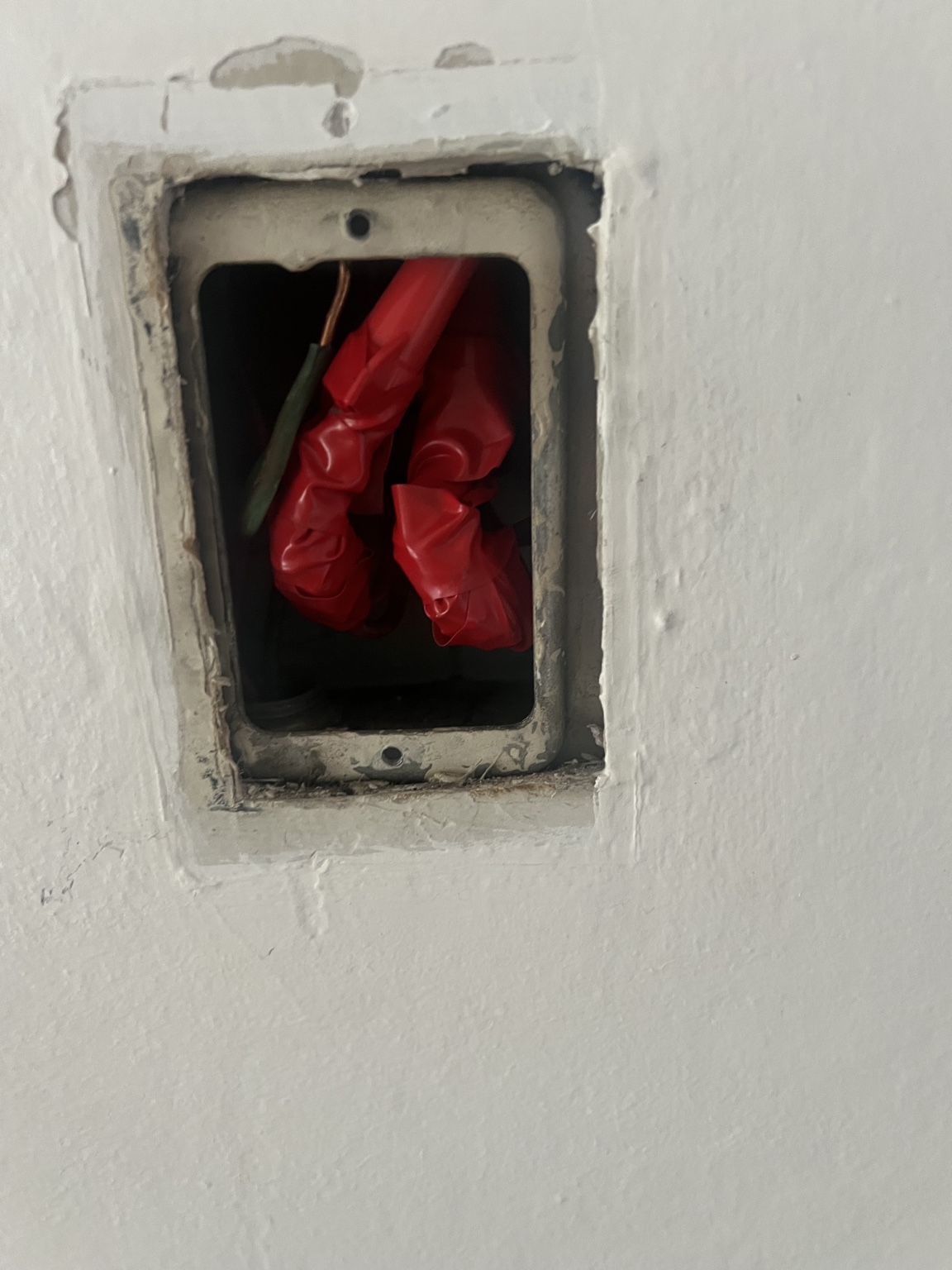 Open wall electrical box with several wire connections wrapped in red tape